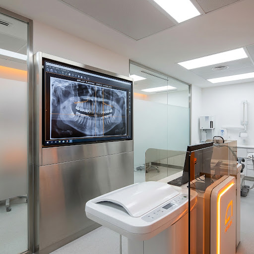 Clínica de radiologia odontológica com monitor exibindo planejamento de implantes e raio-x panorâmico.